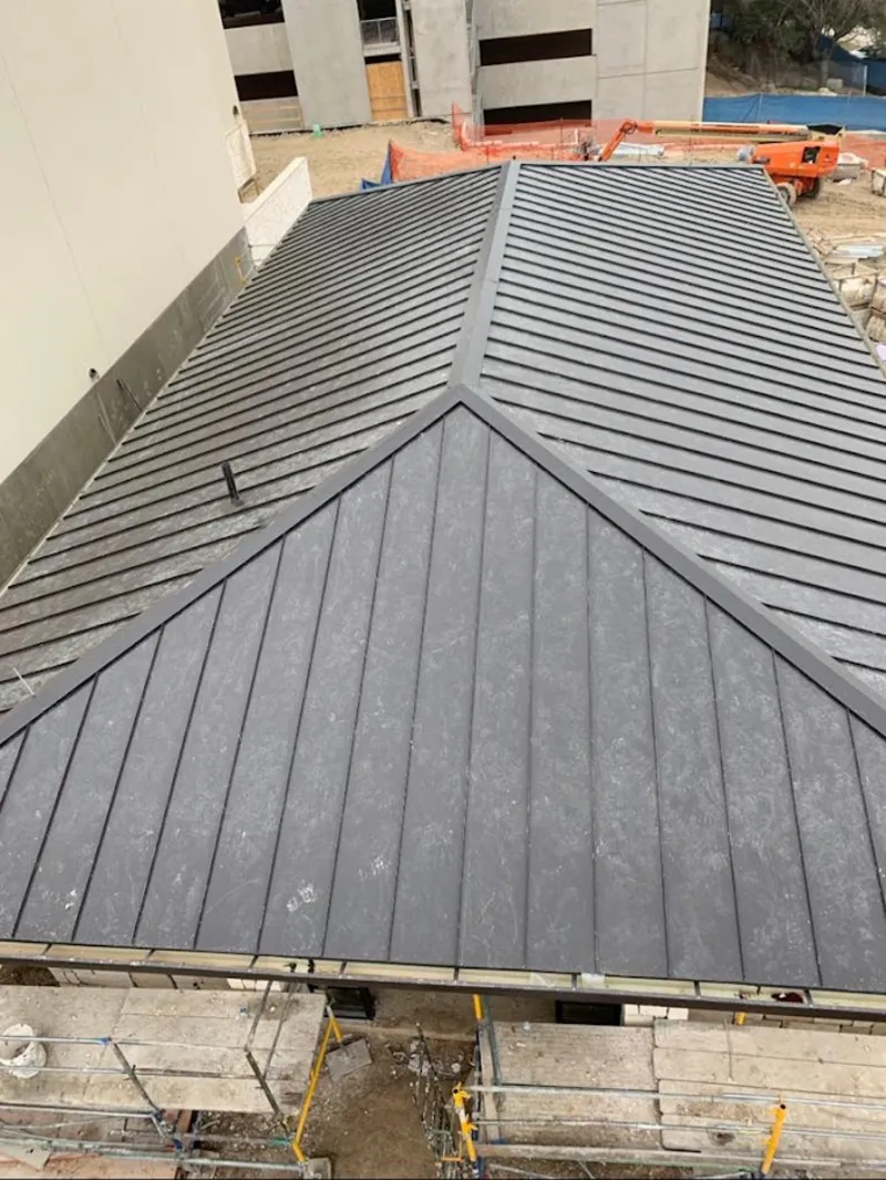 Commercial metal roof construction with crane equipment in Westborough